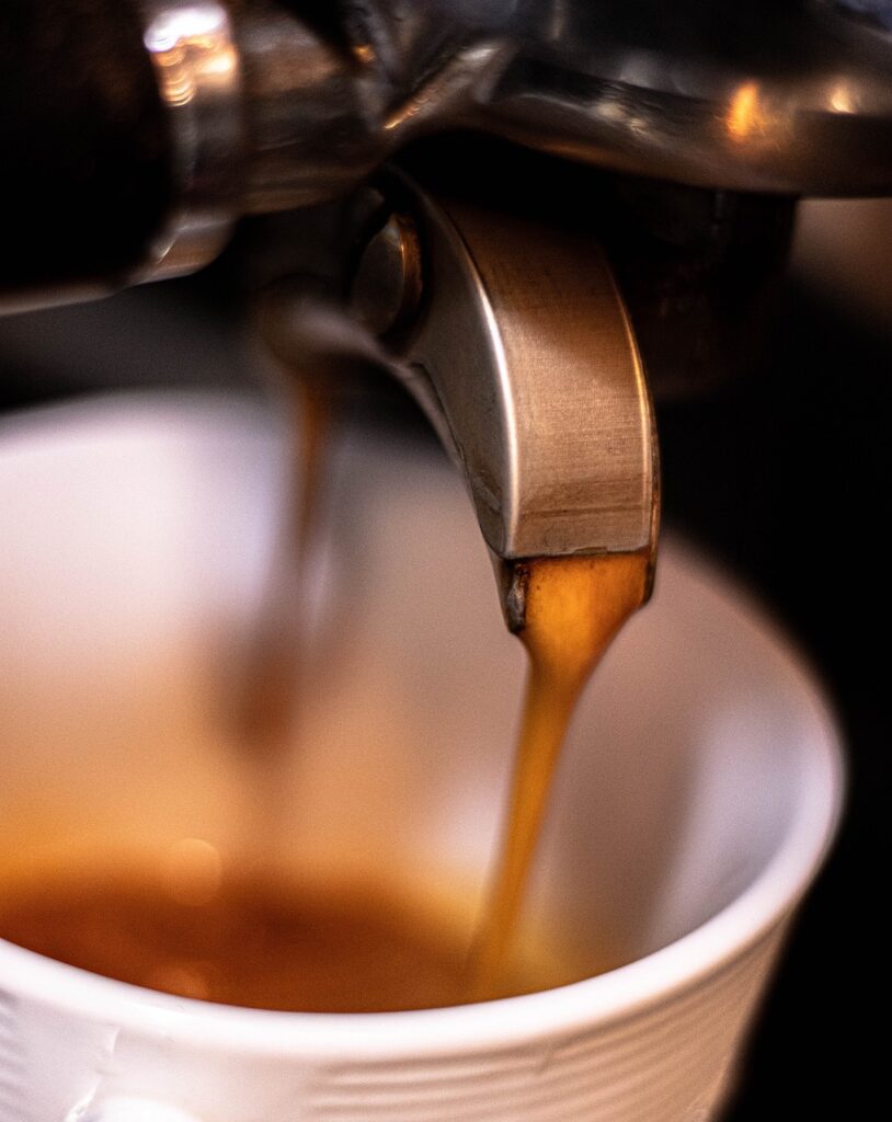 Frischer Kaffee läuft aus Automat in eine Tasse.